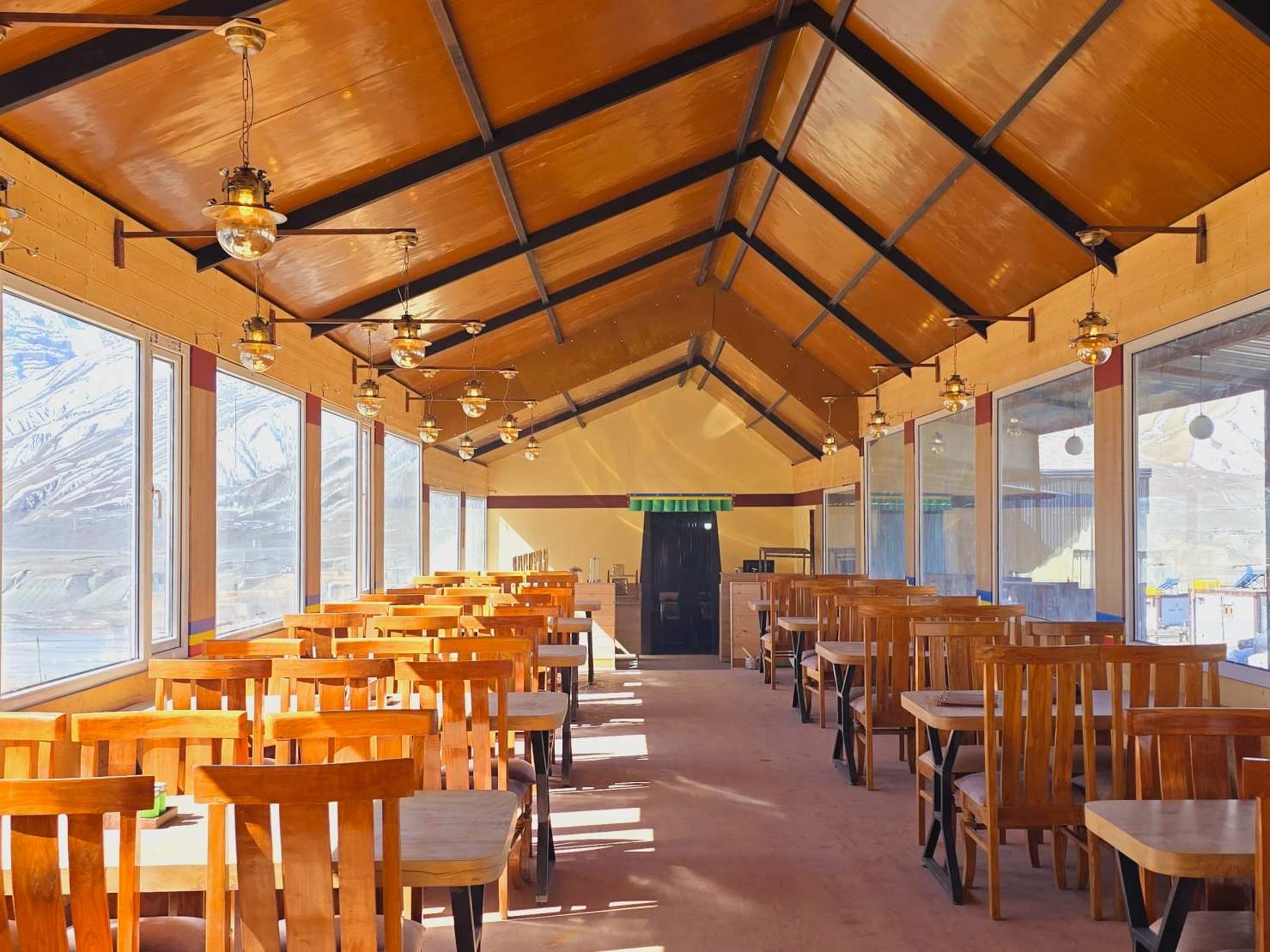 The glass-walled restaurant: rows of wooden tables under a timber roof