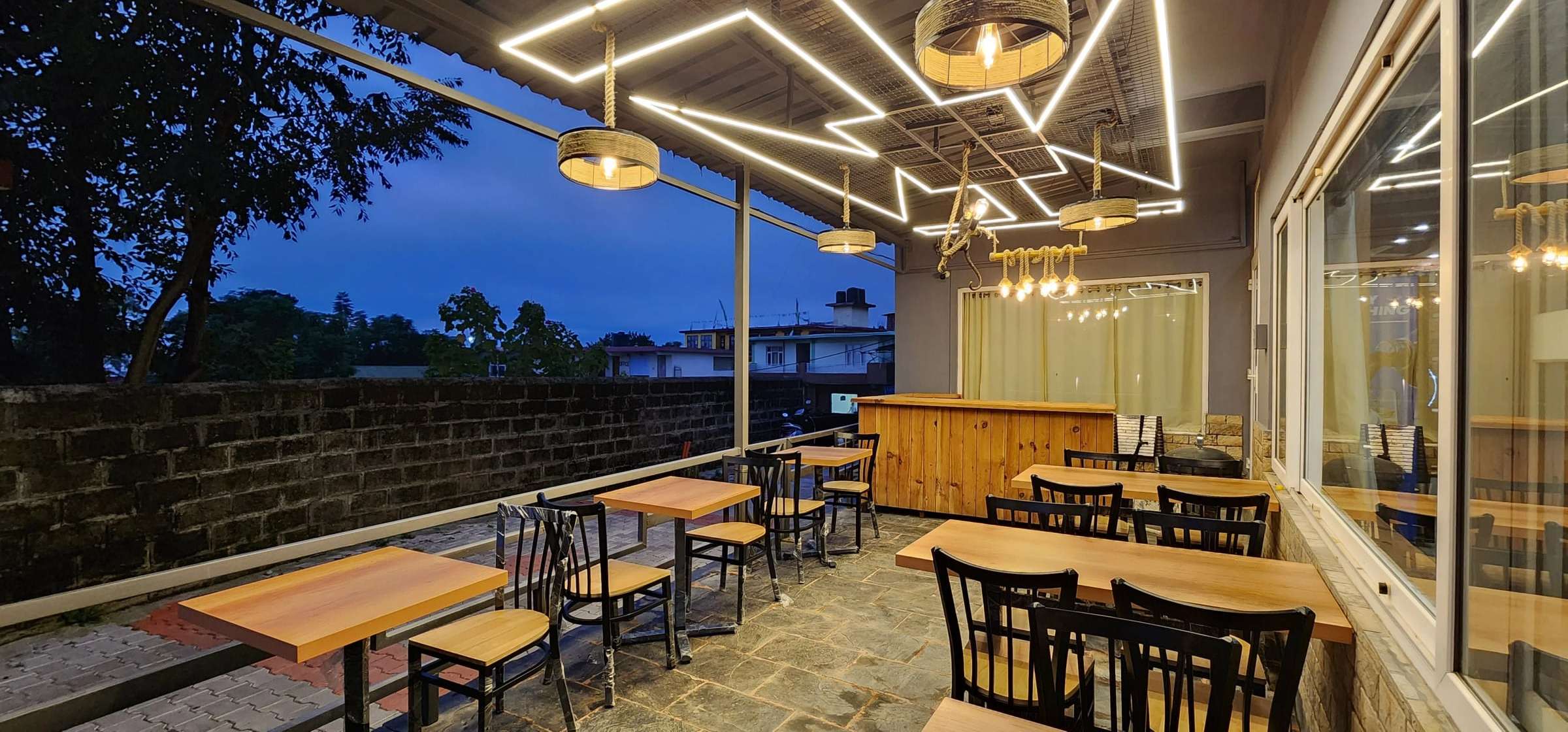 The open-air restaurant terrace at dusk, under a ceiling of zig-zag light strips