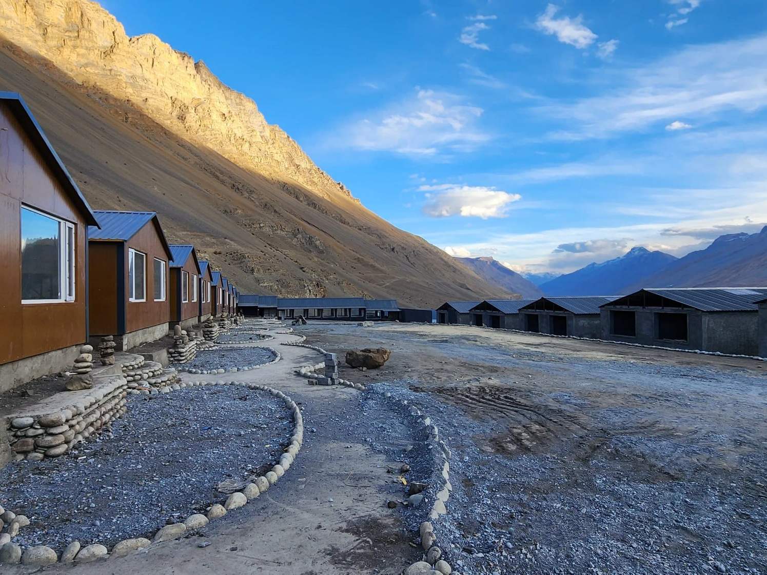 Cottages along a gravel path below the bare mountains of Spiti