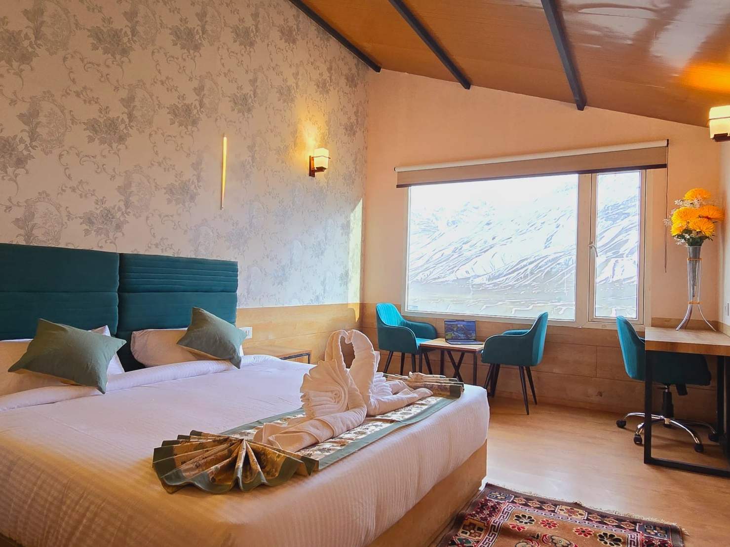 Cozy Queen Mountain View room: a bed with a teal headboard and a window onto snowy slopes