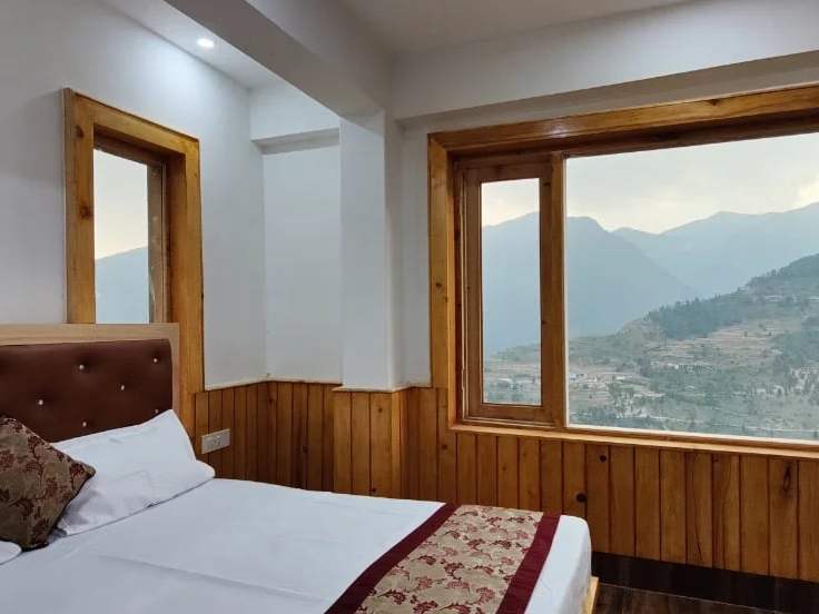 Premium room at Diwan: a wide window over a mountain valley, beside the bed