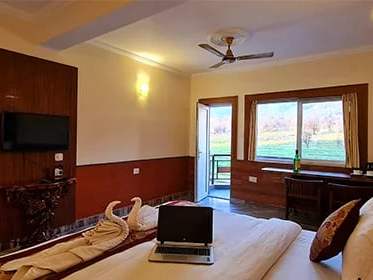 Premium room: a TV, a desk and a glass door open to the balcony over green fields