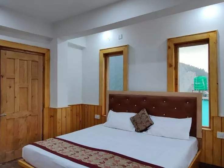 Superior room at Diwan: a bed by pine-framed windows looking onto forested hills
