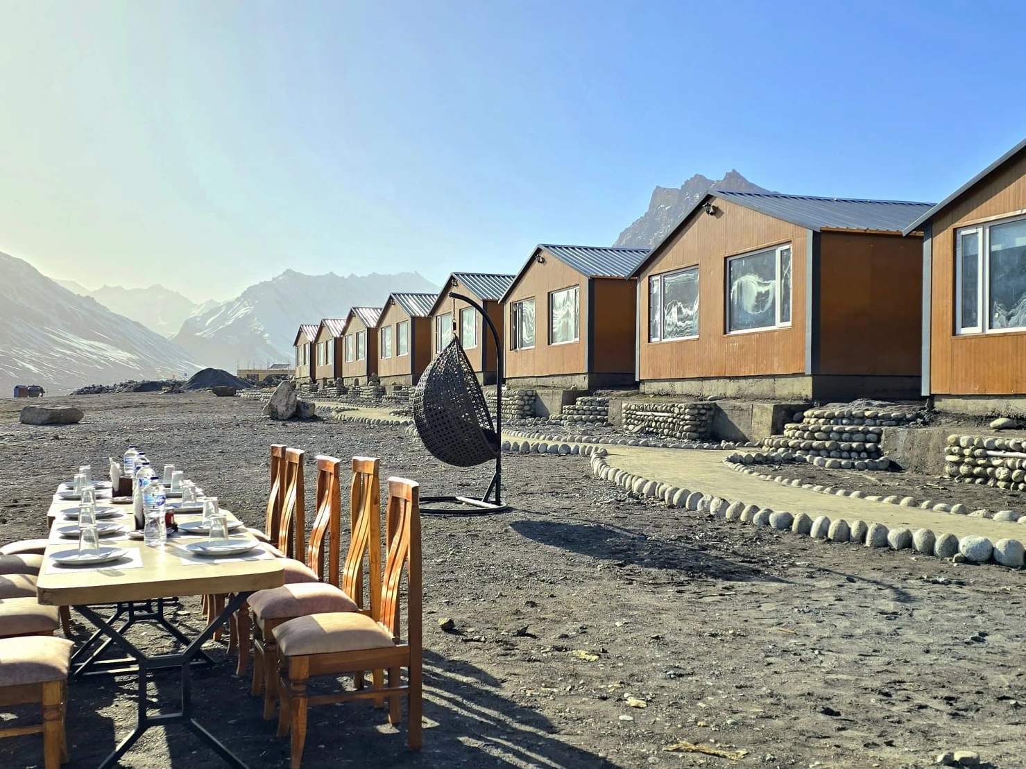 A long table laid outdoors beside the cottages