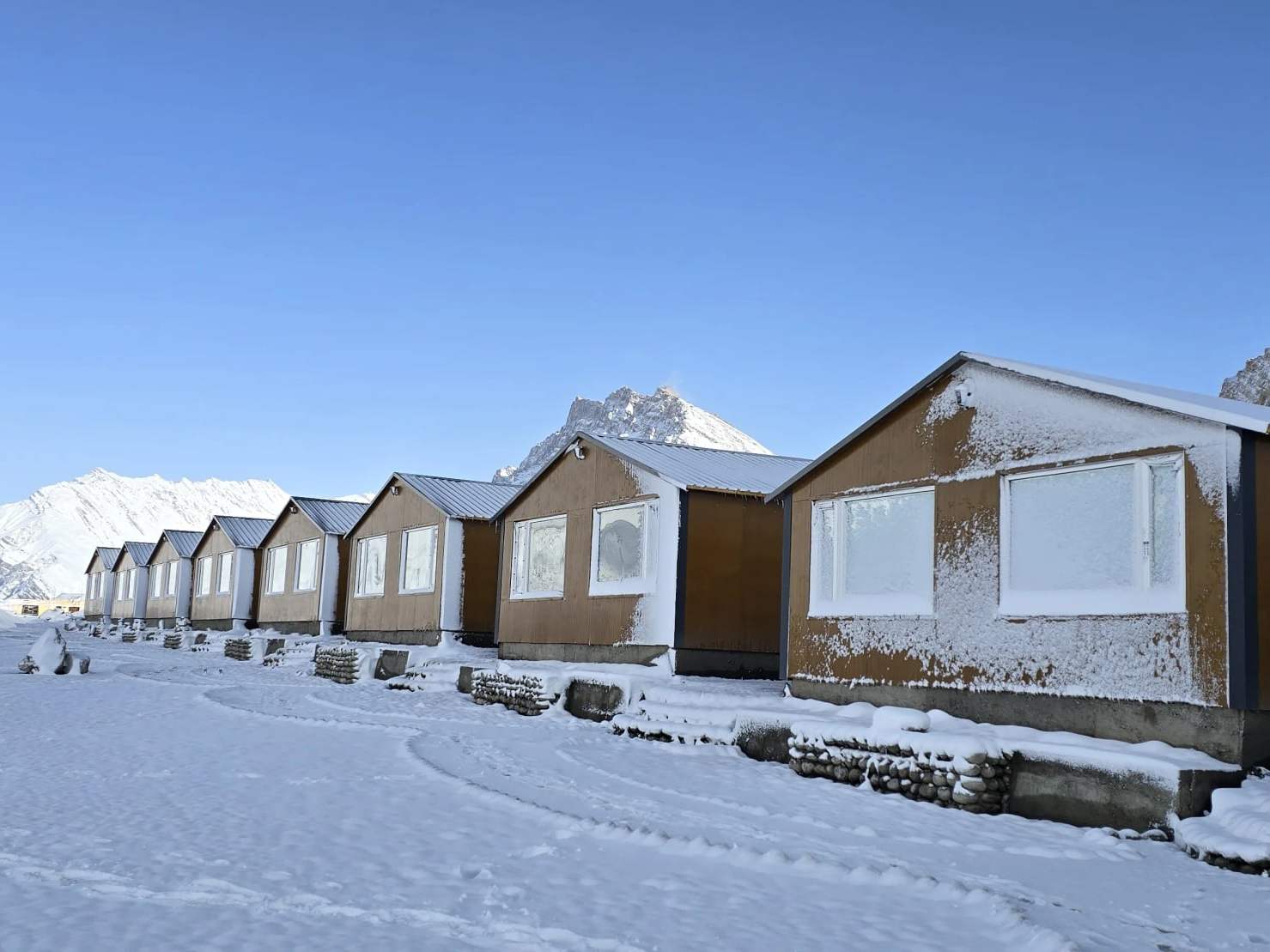 The cottages under snow, with white peaks behind