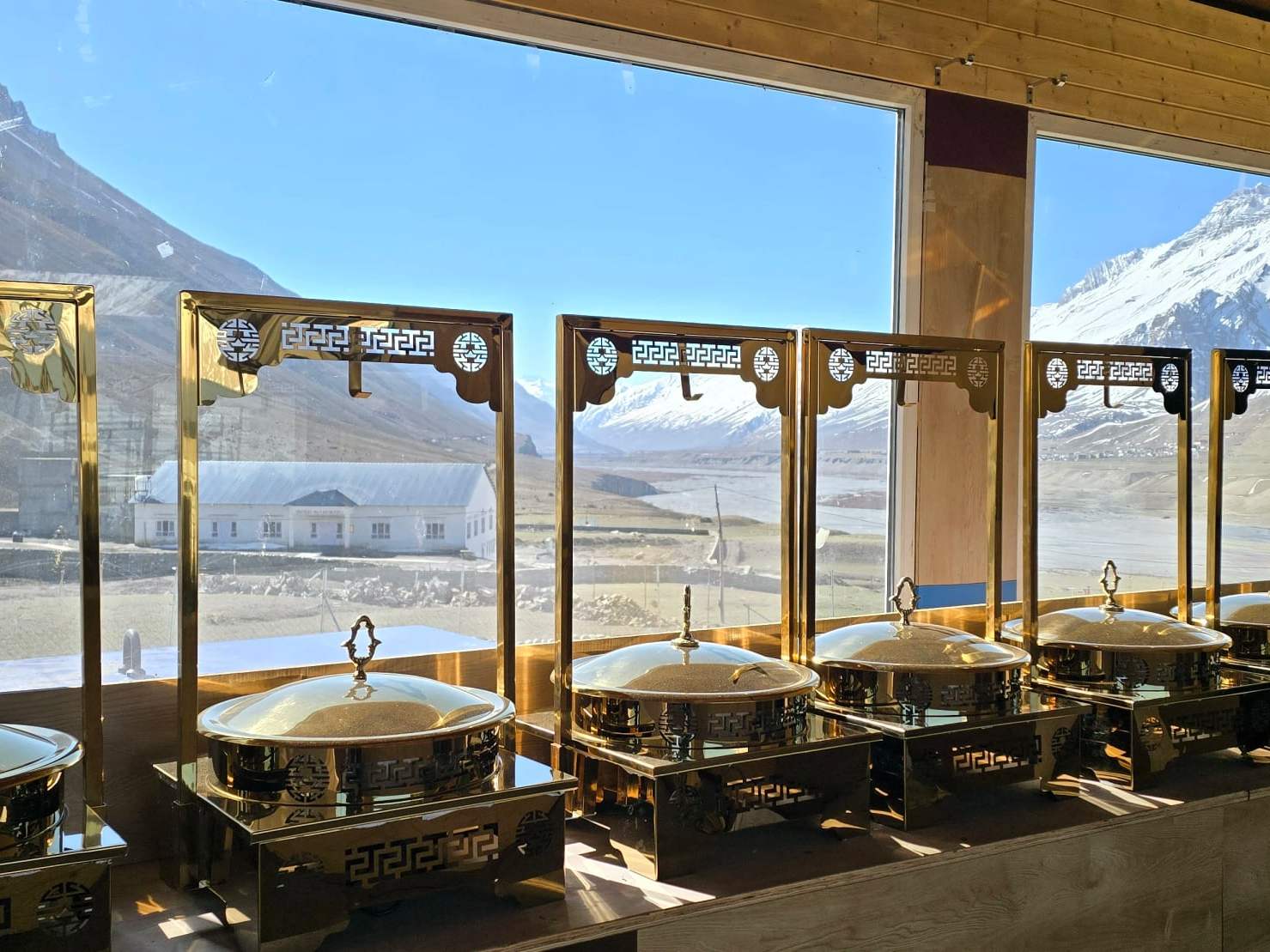 Brass buffet dishes by the restaurant’s windows, with snow peaks outside