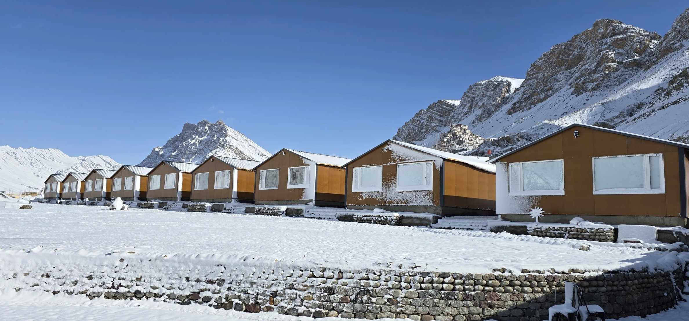 Hotel Spiti Villa’s row of wooden cottages in fresh snow, below the mountains of Spiti